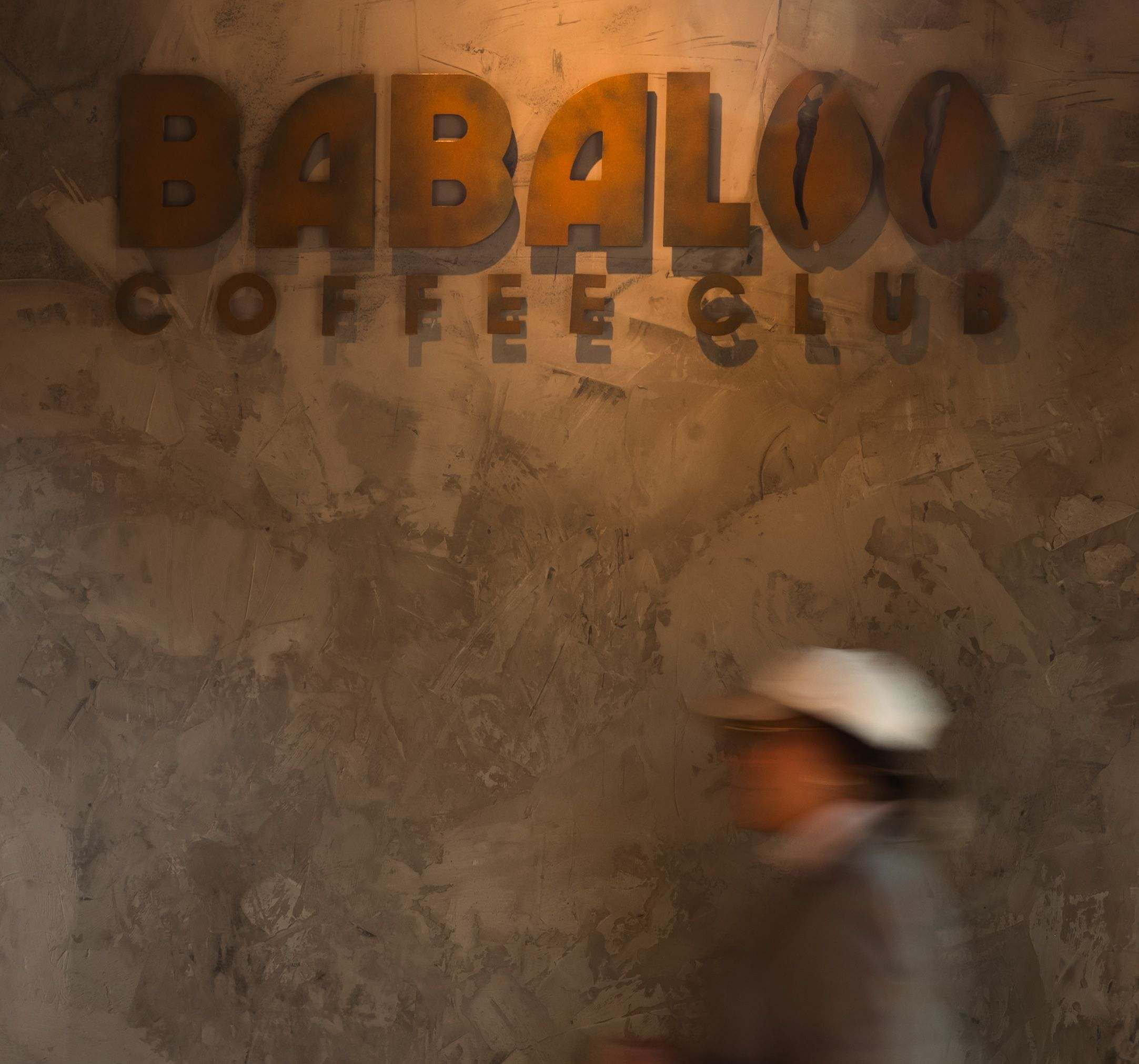 The Babaloo Coffee Club sign lit on a textured wall